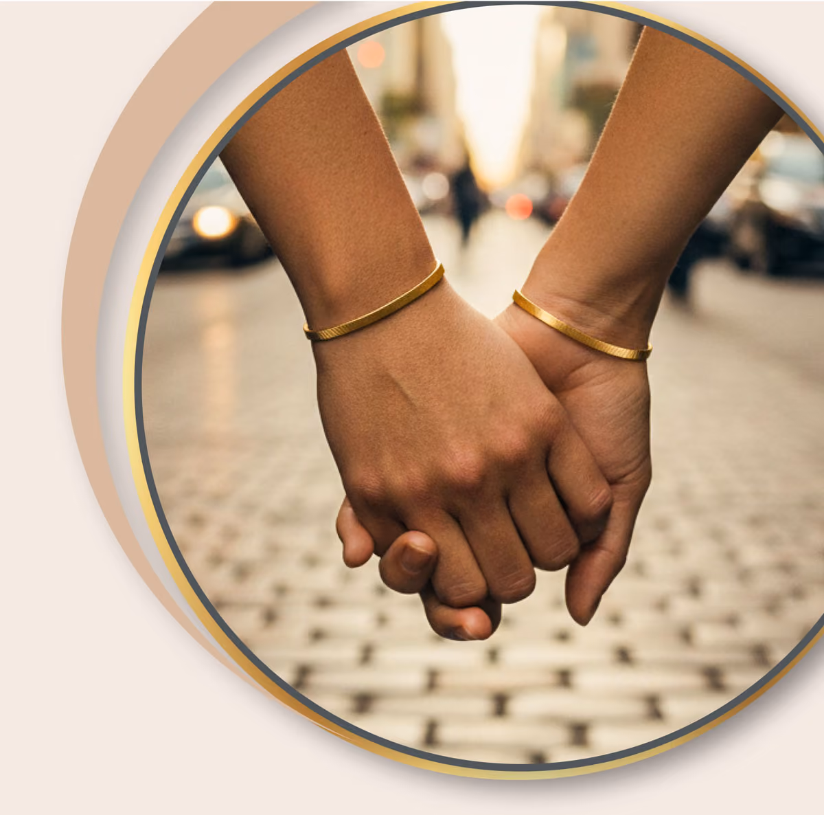 Zwei Hände mit goldenen Armbändern halten einander vor einem verschwommenen Straßenhintergrund.